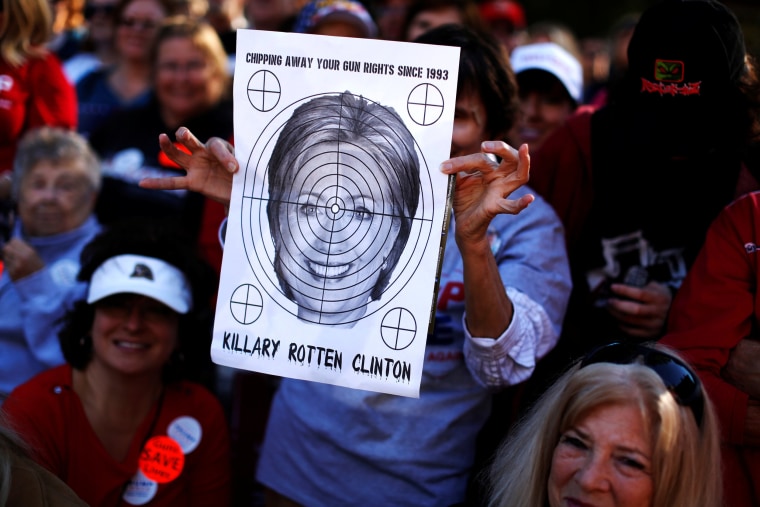 Image: A supporter of Republican U.S. presidential nominee Donald Trump holds a shooting target with image of Hillary Clinton at a campaign rally in Virginia Beach