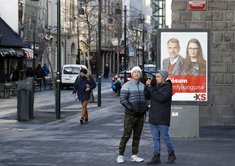 Image: People walk past an social democrats election poster in Reykjavik