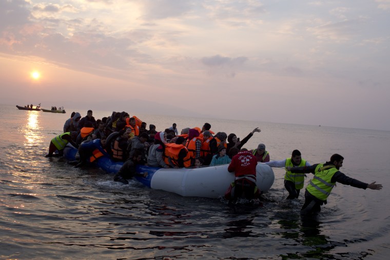 Image: Volunteers help migrants and refugees on a dingy as they arrive at the shore of the northeastern Greek island of Lesbos