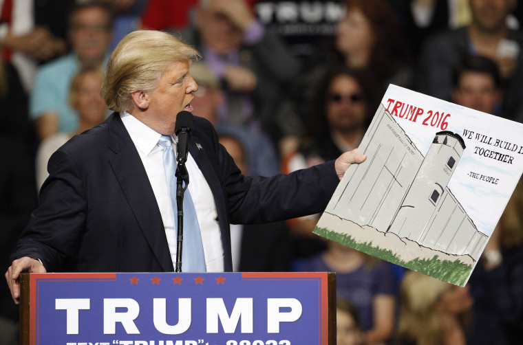 Image: U.S. Republican presidential candidate Donald Trump holds a sign supporting his plan to build a wall between the United States and Mexico that he borrowed from a member of the audience at his campaign rally in Fayetteville North Carolina