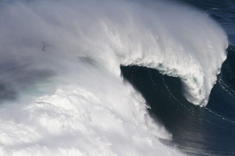 Image: A surfer is caught by a big wave at Praia do Norte