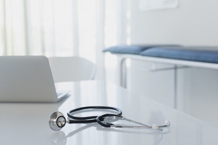 Stethoscope and laptop on white desk in doctors office