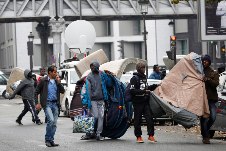 Image: Migrants move tents from a makeshift camp in a street near Stalingrad metro station in Paris