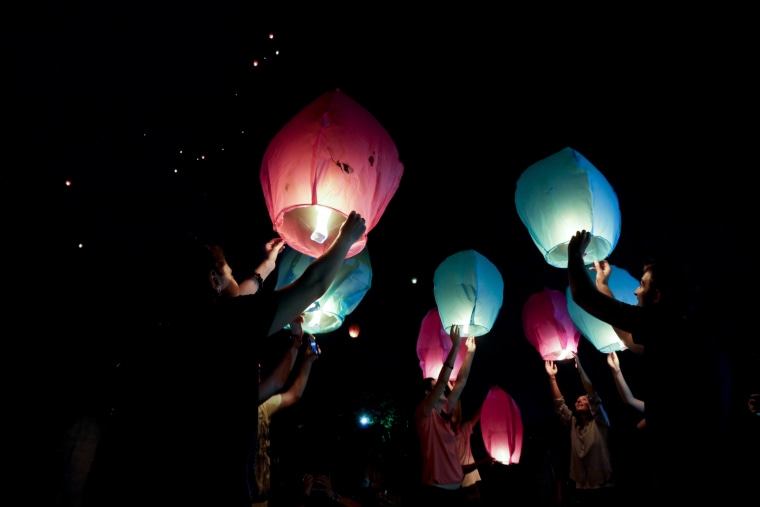 Image: People hold sky lanterns to release during a campaign against the use of firecrackers during Diwali