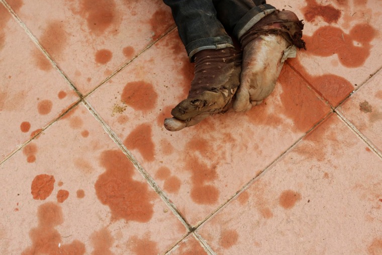 Image: An African migrant lies on the ground after crossing a border fence between Morocco and Spain's north African enclave of Ceuta