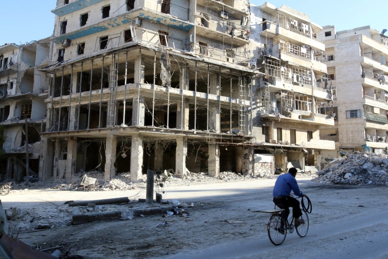 Image: A man rides a bicycle near damaged buildings in Aleppo on Oct. 19, 2016