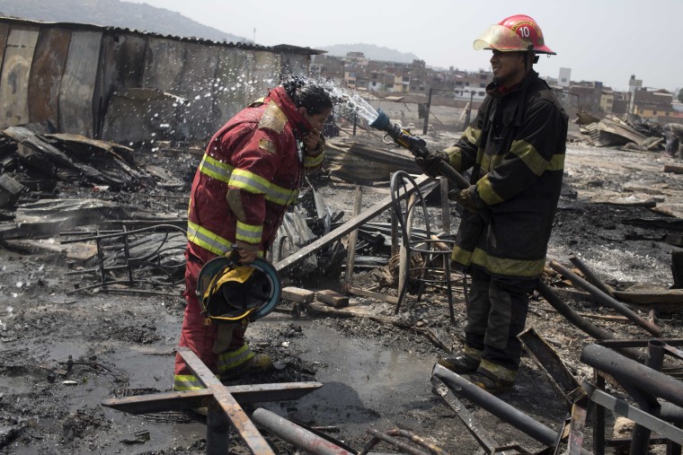 Firemen cool off amid charred debris following an early morning fire that destroyed hundreds of homes, in the shantytown known as Cantagallo, in Lima, Peru, Friday, Nov. 4, 2016.