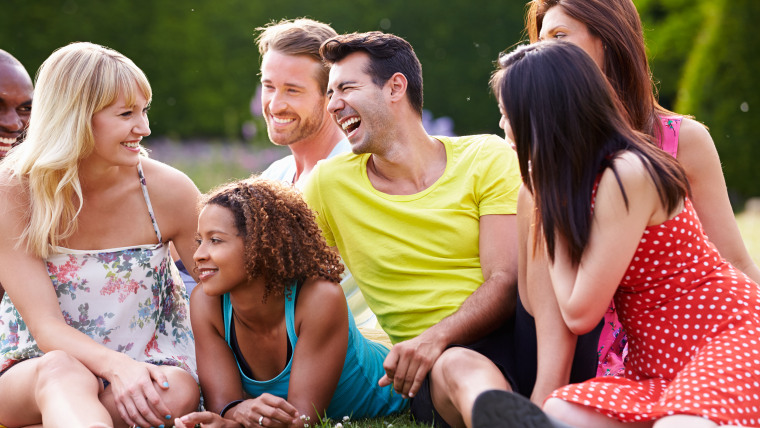 Group Of Friends Sitting On Grass Together