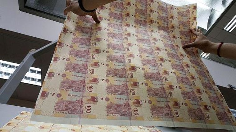 An employee inspects sheets of Mexican hundred pesos notes at the Banco de Mexico printing factory in Mexico City, Mexico