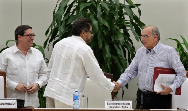 Image: Colombia's FARC lead negotiator Ivan Marquez and Colombia's lead government negotiator Humberto de la Calle shake hands while Cuba's Foreign Minister Bruno Rodriguez looks on, after signing a new peace deal