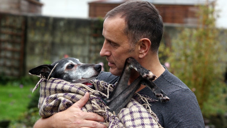 Mark Woods holds dog Walnut before taking him to Porth beach for a final walk