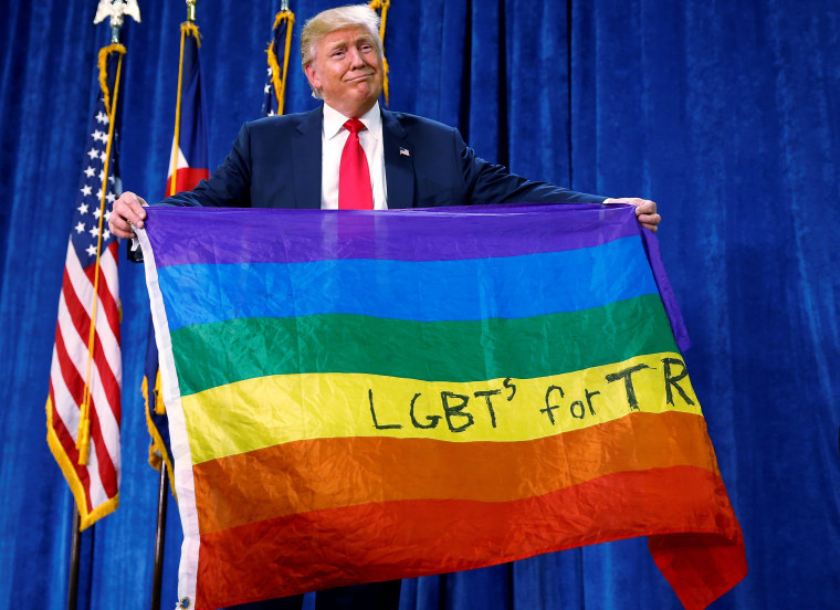 Image: Republican presidential nominee Donald Trump holds up a rainbow flag with "LGBT's for TRUMP" written on it at a campaign rally in Greeley