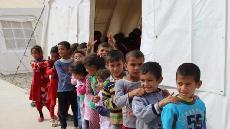 Image: Iraqi school children form a line outside their makeshift classroom