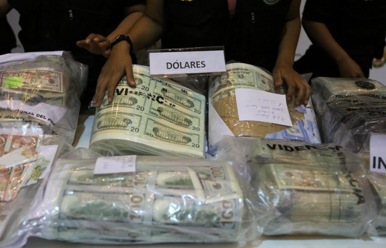 Image: Police officers display seized counterfeit U.S. and Nuevos Soles bills at a news conference in Lima, Peru