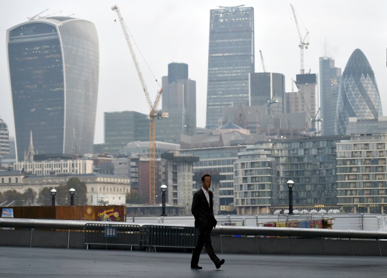 Image: A man walks in front of the City of London financial district of London