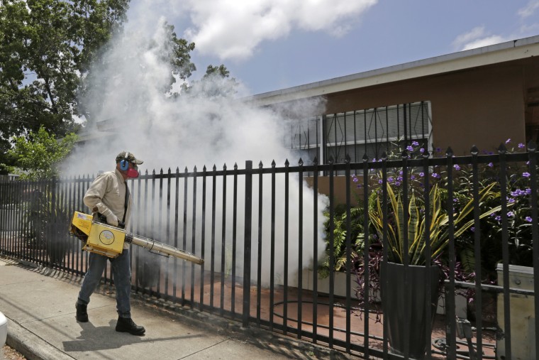 A Miami-Dade County mosquito control worker sprays around a home in the Wynwood area of Miami 