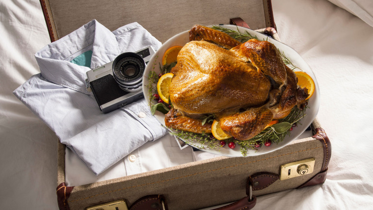 Open suitcase on bed with camera and thanksgiving turkey
