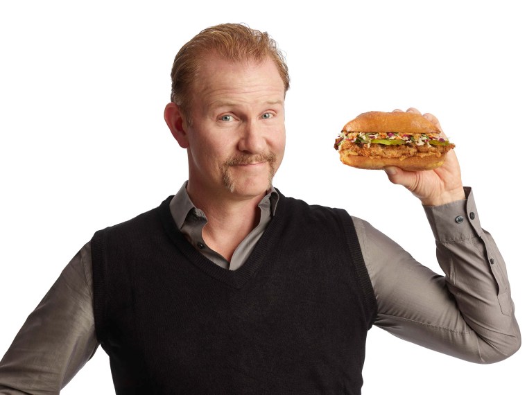 Morgan Spurlock holding a sandwich from Holy Chicken!
