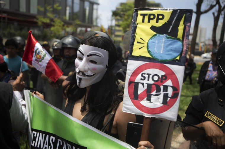 Image: A protester holds signs against the Trans Pacific Partnership (TPP) during a rally in Lima
