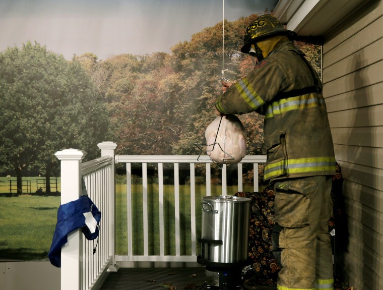Image: Firefighter prepares to drop a Thanksgiving frozen turkey into a deep fryer
