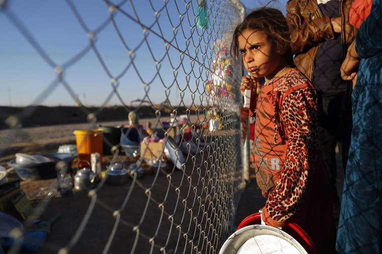 Image:  An Iraqi refugee girl waits with her parents to buy food from a local vendor behind the fence of the Khazir refugee camp near the Kurdish checkpoint of Aski Kalak