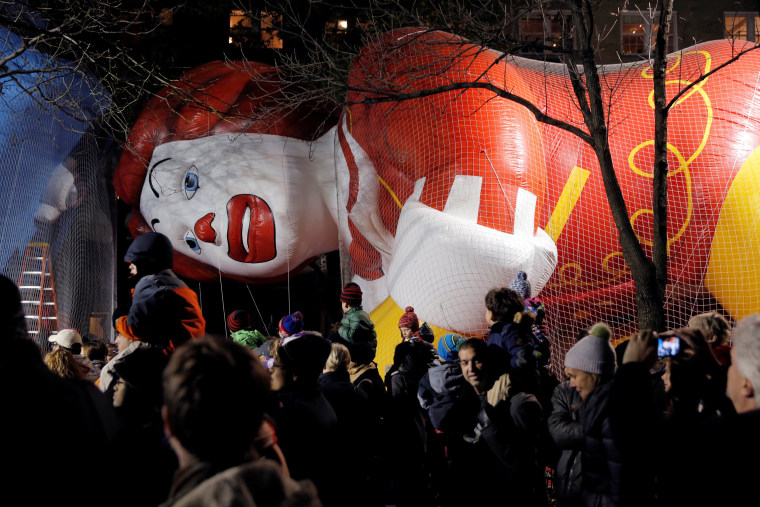 Image: Crowds walk by the Ronald McDonald balloon ahead of the 90th Macy's Thanksgiving Day Parade in Manhattan