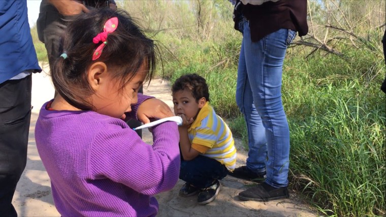 A 3-year-old girl and 5-year-old boy stand at the feet of their mothers, who say they made the long journey to the U.S. from El Salvador.