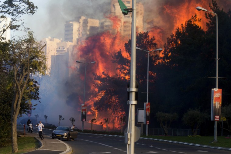 Image: People run as wildfires rages in Haifa, Israel