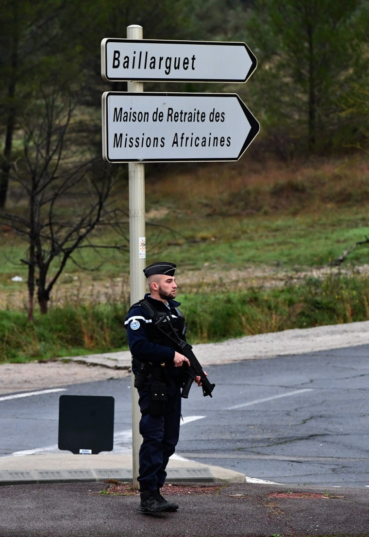 Image: A police officer stands guard on a road in Montferrier-sur-Lez, France
