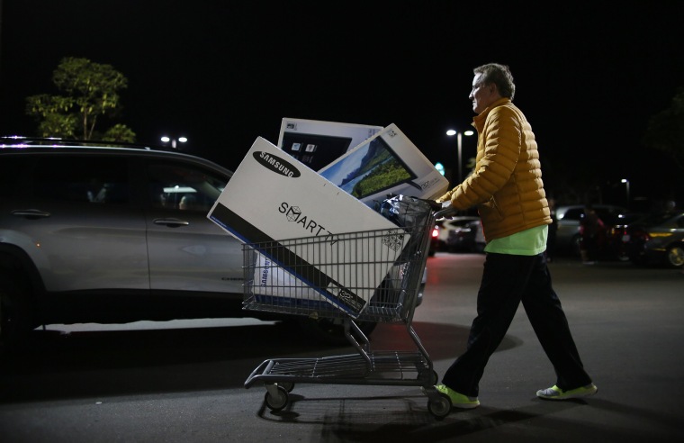 Image: Shoppers exit a Best Buy after purchasing electronic items during Black Friday sales in San Diego