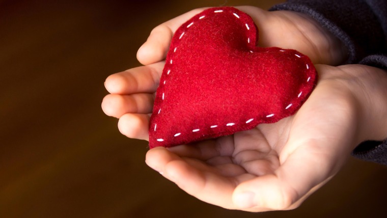 Red heart in child hands, hand made gift, valentine day and family love concept, close up, horizontal