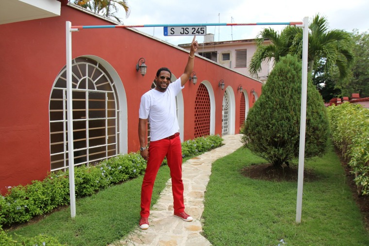 Former Olympian Javier Sotomayor stands under a custom high-jump bar outside his home, which stands at 2.43 meters -- his world record.