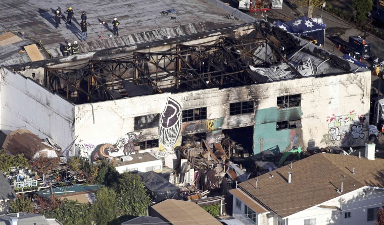 Image: Recovery teams examine the remains of the warehouse that caught fire in Oakland