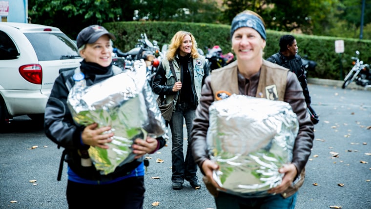 Two bikers prepare to make a delivery of frozen breast milk.