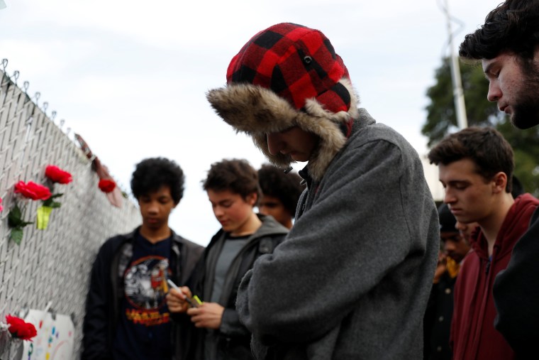 Image: Teenagers gather to pay their respect at a makeshift memorial near the scene of a fatal warehouse fire in the Fruitvale district of Oakland, California