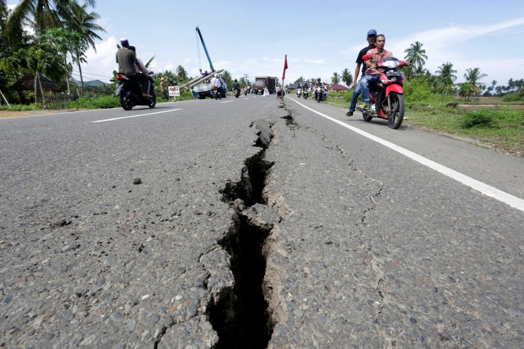 Image: Motorcyclists pass a damaged section of a road following an earthquake in Meuredu, Pidie Jaya, in the northern province of Aceh