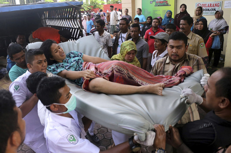 Image: Hospital workers and family members carry a woman injured in an earthquake at a hospital in Pidie