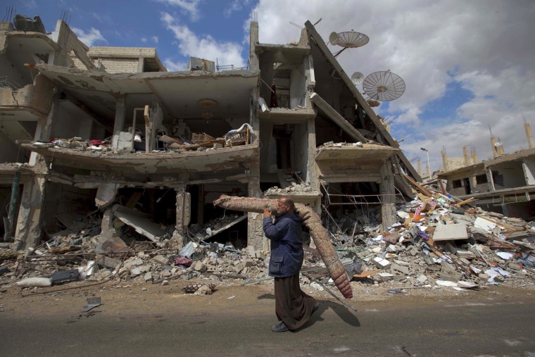 A Syrian man carries a carpet through a devastated part of the town of Palmyra in April.