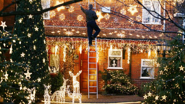 Man hanging Christmas lights outside.