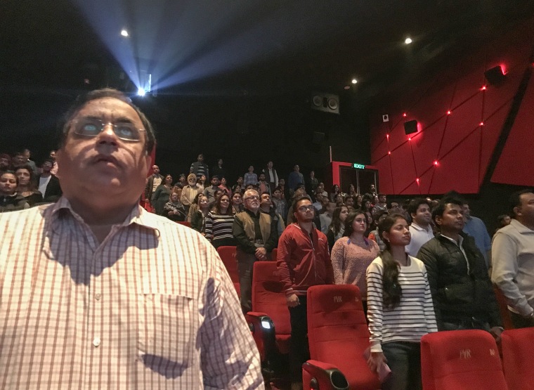 Image: Indian movie goers stand up as national anthem is played at a movie hall before the screening of a movie in Jammu
