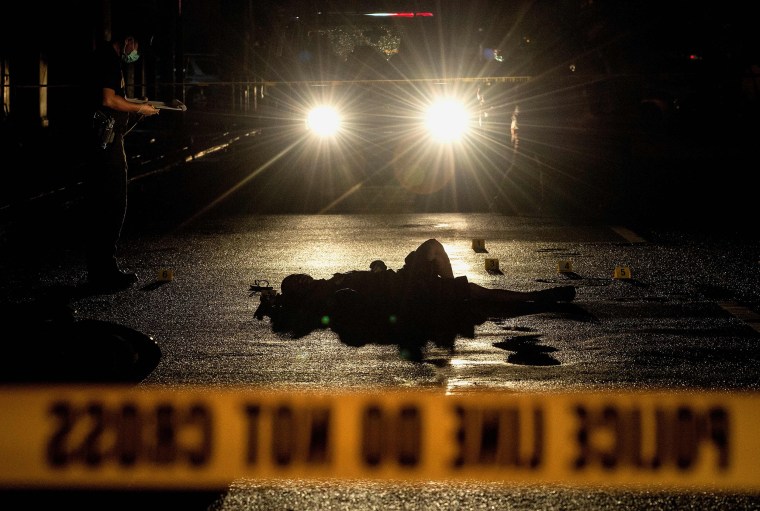 Image: This picture taken on October 29, 2016 shows police officers investigating a crime scene where two alleged drug dealers were gunned down by unidentified men in Manila.