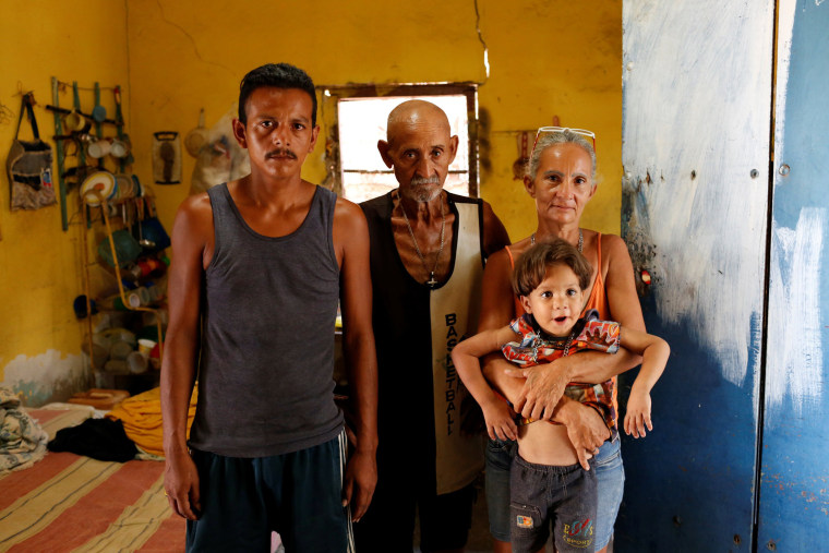 Image: Zulay Pulgar, holds her son Emmanuel, next to her husband Maikel Cuauro and her father Juan Pulgar while they pose for a portrait in their house in Punto Fijo