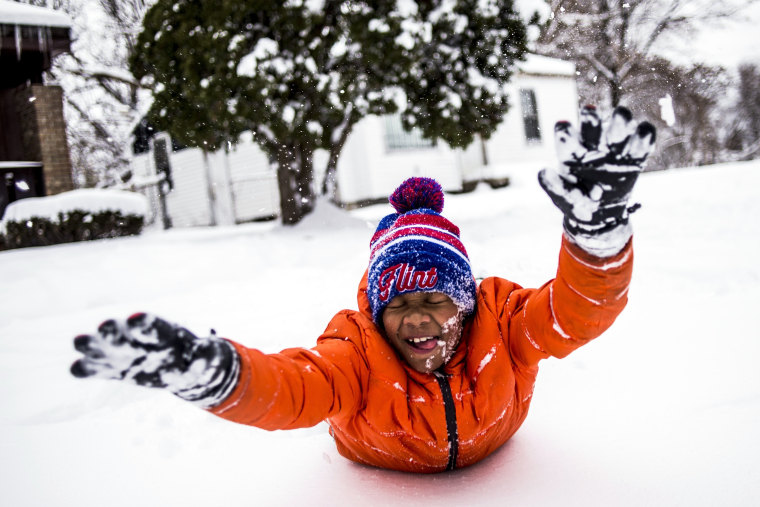 Image: Steven Washington, 9, dives faces first into a fresh pile of snow, taking a break from shoveling his grandmother's driveway after school was called off for a snow day Monday, Dec. 12, on Flint, Michigan's north side.