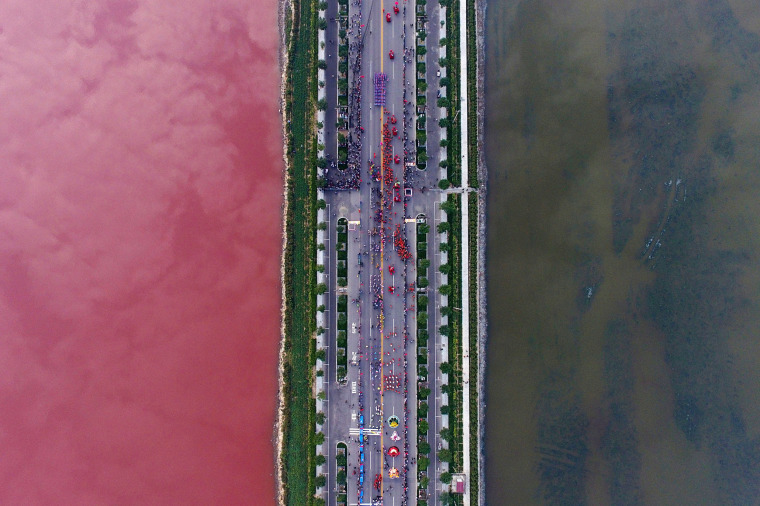 Image: A salt lake which is separated by a road, shows parts of it in different colours due to algae, in Yuncheng, Shanxi Province, China