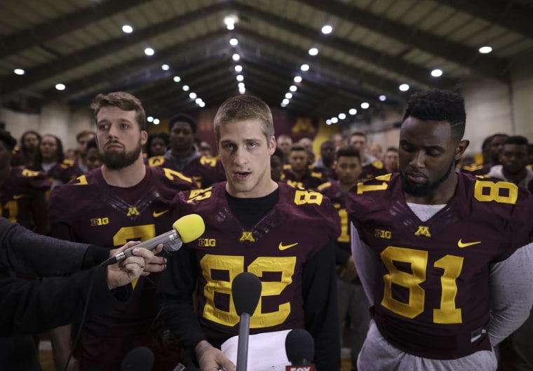 University of Minnesota wide receiver Drew Wolitarsky, flanked by quarterback Mitch Leidner, left, and tight end Duke Anyanwu stands in front of other team members as he reads a statement on behalf of the players in the Nagurski Football Complex in Minneapolis, Minn., Thursday night, Dec. 15, 2016.