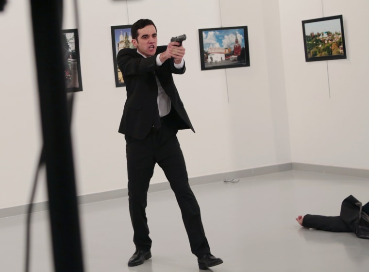 Image: An unnamed gunman gestures after shooting the Russian Ambassador to Turkey