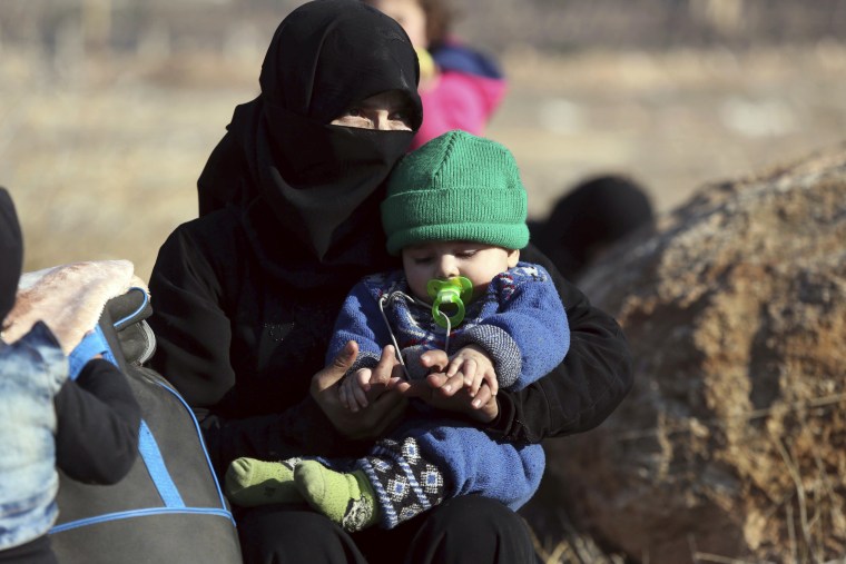 Image: A Syrian woman holding a child who were  evacuated from the embattled Syrian city of Aleppo