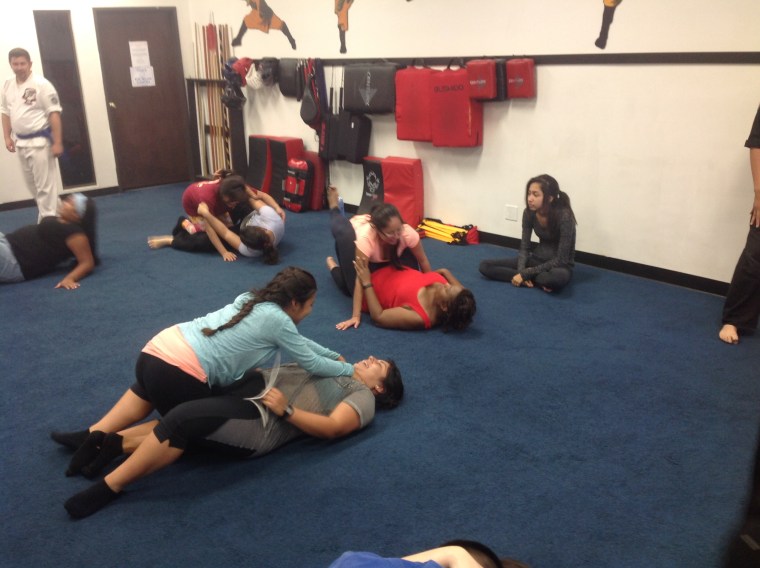 Participants from Gomez' self-defense workshop practice top mount attack positions with a choke hold. The exercise involved working on controlled escapes.