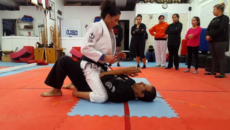 A student performs a role as an attacker exerting a chokehold on instructor Maurice Gomez.