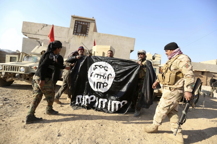 Image: Iraqi army soldiers celebrate with seized ISIS flag